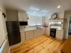 una cucina con frigorifero nero e orologio sul muro di Glendale Cottage a Daylesford