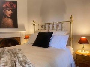 Un dormitorio con una cama blanca con un retrato de una mujer en Glendale Cottage, en Daylesford