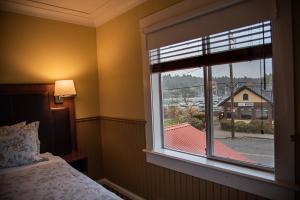 a bedroom with a window with a view of a building at Salt Spring Inn in Ganges