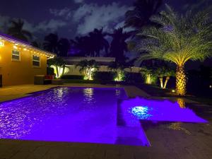 - une piscine avec des lumières violettes dans une arrière-cour la nuit dans l'établissement New! Waterfront Heated Pool & Jacuzzi 2 mi to Beach - Fishing Pier Relaxing SPA & Hammock, à Fort Lauderdale