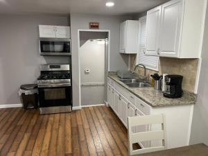 a kitchen with white cabinets and a wooden floor at Gorgeous 3 Bdrm vacation house in Detroit