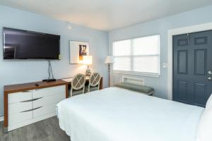 1 dormitorio con 1 cama, escritorio y TV en Echo Sails Motel, en Clearwater Beach