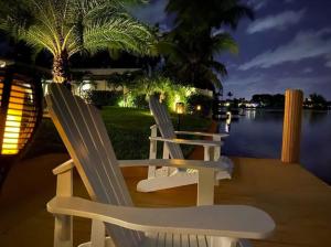 dos sillas blancas sentadas en un muelle junto al agua por la noche en New! Waterfront Heated Pool & Jacuzzi 2 mi to Beach - Fishing Pier Relaxing SPA & Hammock, en Fort Lauderdale