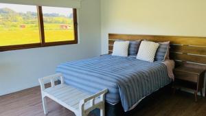 1 dormitorio con cama, banco y ventana en Casa Familiar Puerto Varas en La Ensenada