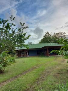 a house with a green roof and a grass yard at Casa Tabacón in Puerto Jiménez