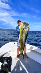 a man standing on a boat holding a large fish at Casa Tabacón in Puerto Jiménez