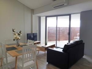 a living room with a black couch and a dining room table at Waverley apartment E-one bedroom wifi available in Perth