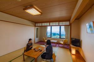 deux femmes assises dans un salon avec une table dans l'établissement Kyukamura Sanuki-Goshikidai, à Sakaide