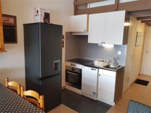 a kitchen with a black refrigerator and white cabinets at Duplex 4 pers - 1 ch - Centre station - Balcon Sud - Wifi - Parking - FR-1-393-114 in Saint-Michel-de-Chaillol +5 photos