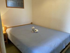 un animale di peluche seduto su un letto in una stanza di Appartement Puy-Saint-Vincent, 2 pièces, 4 personnes - FR-1-330G-36 a Puy-Saint-Vincent