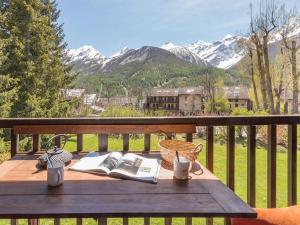 Una mesa de madera con un libro en un balcón con montañas. en Charmant T2 mezzanine 5 pers, balcon sud, proche centre et pistes, parking privé - Le Monêtier les Bains - FR-1-330F-158, en Le Monêtier-les-Bains