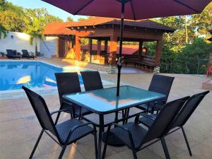 un tavolo e sedie con ombrellone accanto a una piscina di Villa Amila By Hospedify Hermosa Villa para 20 personas y a 4 minutos del Río de Jarabacoa a Jarabacoa