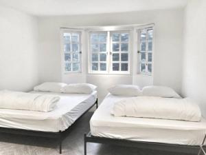 two beds in a room with two windows at 80 Colonie Fraser's Hill 16 Pax in Bukit Fraser