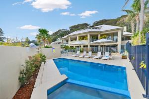 a house with a swimming pool in front of a house at The Masthead Iluka Apartment Luxury and Style in Palm Beach