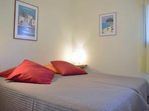 a bedroom with a bed with two red pillows at Le Lavandou : T2 avec 4 couchages, terrasse, parking en option, animaux admis - FR-1-251-212 in Le Lavandou