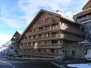 duży budynek z drewnianymi balkonami w śniegu w obiekcie Appartement Méribel, 1 pièce, 4 personnes - FR-1-180-372 w mieście Les Allues