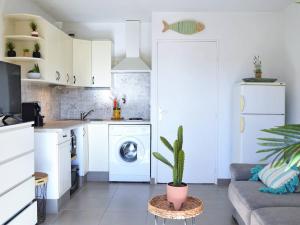 a white kitchen with a washing machine and a plant at Appartement Le Lavandou, 1 pièce, 4 personnes - FR-1-251-232 in Le Lavandou