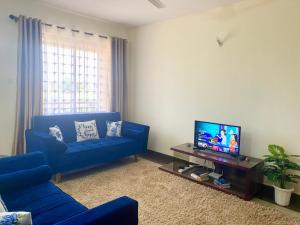 a living room with a blue couch and a tv at Dala Heights in Mombasa