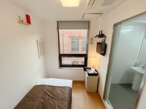 um quarto com uma cama, um lavatório e uma janela em K9 Myeongdong Hotel em Seul