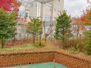 eine Backsteinmauer in einem Garten mit Bäumen in der Unterkunft K9 Myeongdong Hotel in Seoul