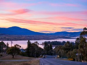 a road with a view of a lake and mountains at Razorback 2 in Jindabyne