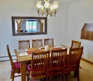 a dining room table with chairs and a chandelier at Top Deck by Kristall Apartments in Jindabyne