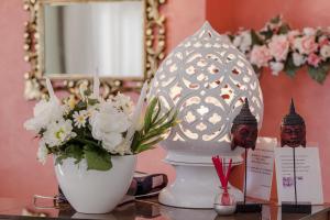 un tavolo con un vaso di fiori e uno specchio di Hotel Bisanzio a Cesenatico