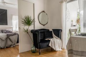a living room with a black chair and a mirror at The White Cottage Byron Bay in Suffolk Park