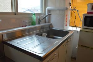 kuchnia z umywalką ze stali nierdzewnej i oknem w obiekcie Zenibako House 3F-RoomA w mieście Otaru