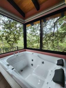 eine große Badewanne in einem Zimmer mit Fenstern in der Unterkunft Cabaña Nala de lujo para parejas in Mazamitla