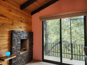 ein Wohnzimmer mit einem Kamin und einem großen Fenster in der Unterkunft Cabaña Nala de lujo para parejas in Mazamitla