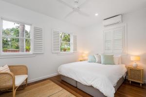 a white bedroom with a bed and two windows at Espadrille Tres in Byron Bay +10 photos