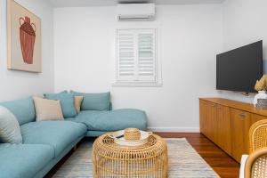 a living room with a blue couch and a tv at Espadrille Tres in Byron Bay