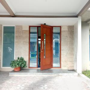a wooden door on a house with a potted plant at Mutiara Balecatur Guest House in Yogyakarta