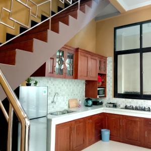 a kitchen with wooden cabinets and a staircase at Mutiara Balecatur Guest House in Yogyakarta