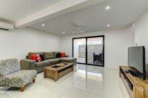 a living room with a couch and a tv at Unit 3 Everdell Street in Bargara