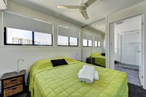 a bedroom with a green bed and some windows at Unit 3 Everdell Street in Bargara