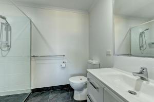 a white bathroom with a toilet and a shower at Unit 3 Everdell Street in Bargara +7 photos