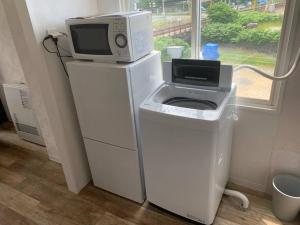 a microwave sitting on top of a stand with a washing machine at Zenibako House 3F-RoomC in Otaru