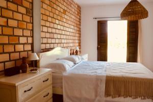 a bedroom with a white bed and a brick wall at Casa com piscina aquecida, privativa,diarista, em condomínio, Bonito-Pe in Bonito