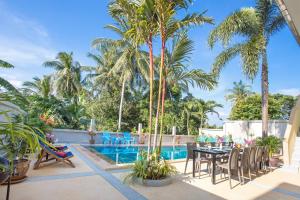 Spacious Family 5BR Villa Nikkie 3, Big Garden & Pool في شاطئ راوايْ: فناء مع طاولة وكراسي بجوار حمام سباحة