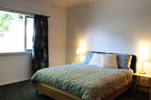 1 dormitorio con 1 cama con 2 lámparas y una ventana en Hoopers Cottage en Aldgate