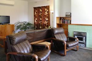 a living room with two leather chairs and a couch at Hoopers Cottage in Aldgate