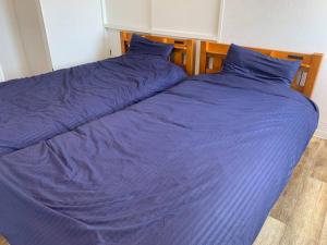 ein großes Bett mit violetter Bettwäsche und blauen Kissen in der Unterkunft Zenibako House 3F-RoomD in Otaru