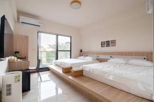 a bedroom with two beds and a large window at 余你相寓 in Neipu