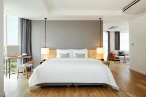 ein Schlafzimmer mit einem großen weißen Bett und einigen Stühlen in der Unterkunft Casa 17 Hotel Bangkok in Bangkok