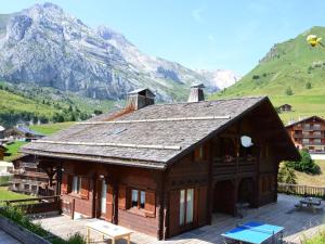 a large wooden house with mountains in the background at Chalet Le Grand-Bornand, 5 pièces, 15 personnes - FR-1-391-24 in Le Grand-Bornand