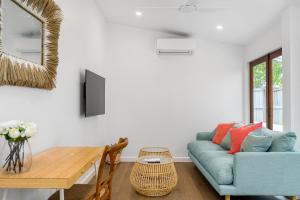 a living room with a blue couch and a table at Espadrille Casita in Byron Bay