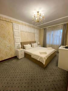 Un dormitorio con una cama grande y una lámpara de araña. en ORZU HOTEL, en Namangan