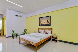 een slaapkamer met een bed en een gele muur bij Capital O Elite Stay Jp Nagar Near SRI SATHYA GANAPATHI SHIRDI SAIBABA Temple in Bangalore